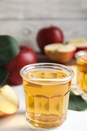 Photo of Glass of delicious apple cider on white table. Space for text
