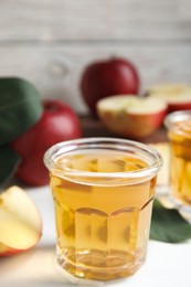 Glass of delicious apple cider on white table. Space for text