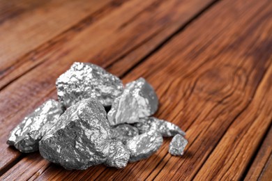 Pile of silver nuggets on wooden table, closeup. Space for text