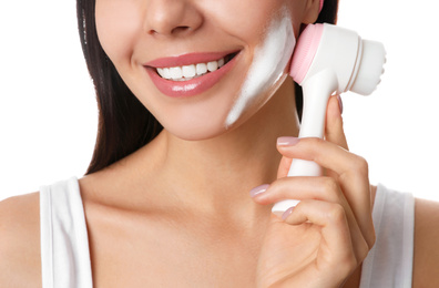 Young woman using facial cleansing brush on white background, closeup. Washing accessory