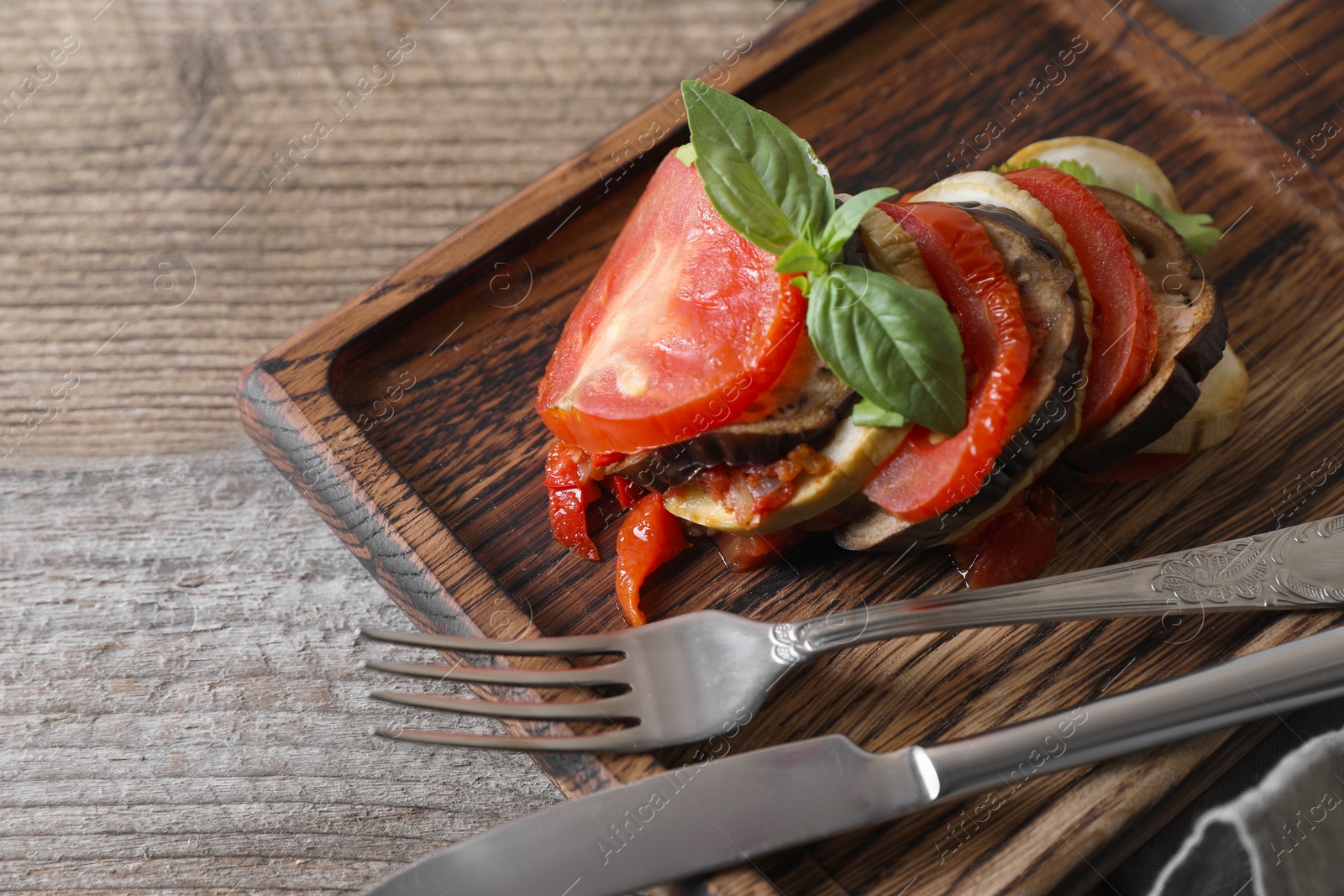 Photo of Delicious ratatouille served with basil on wooden table, closeup