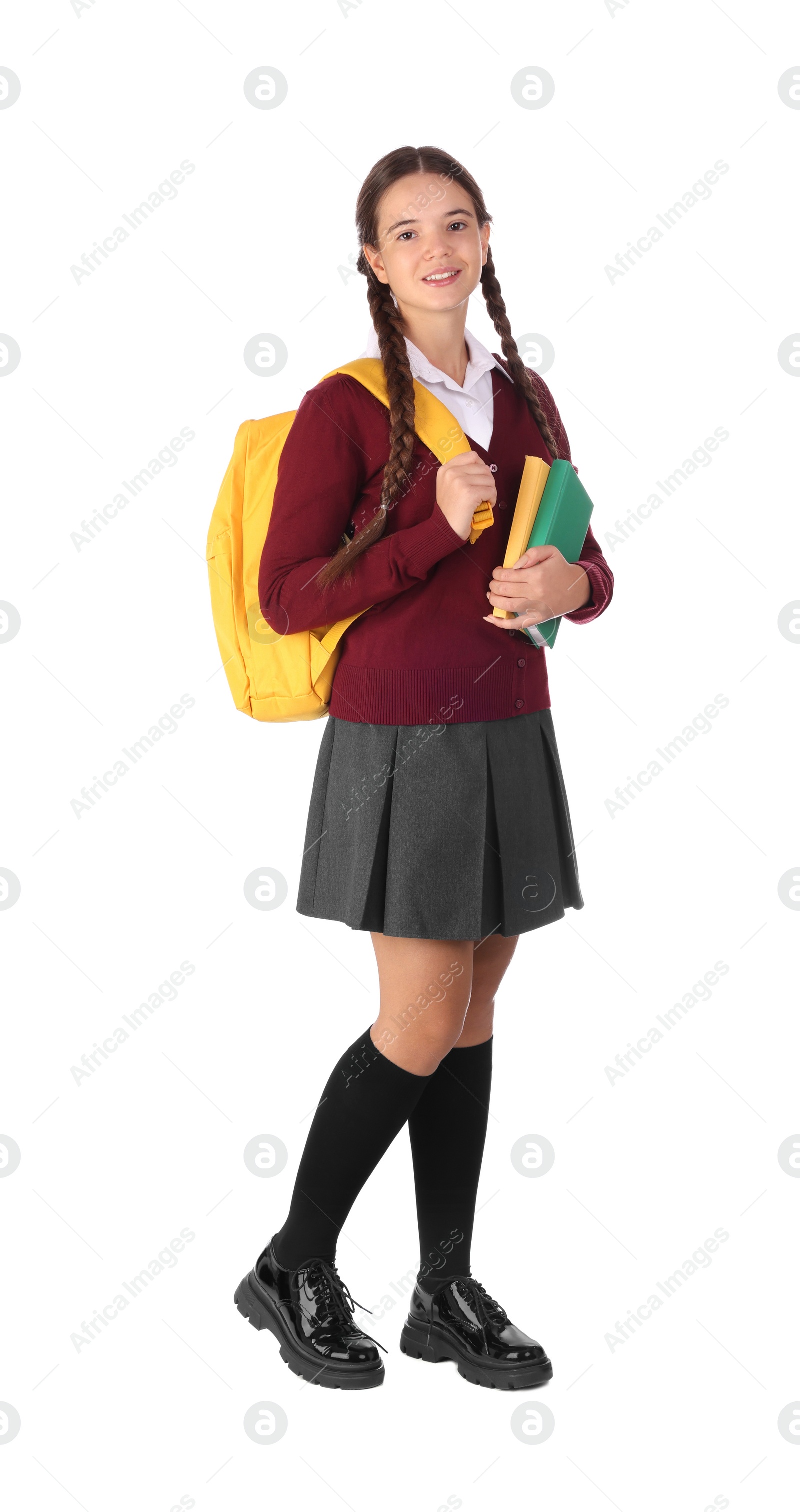 Photo of Teenage girl in school uniform with books and backpack on white background