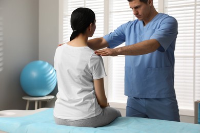 Photo of Orthopedist examining woman in clinic. Scoliosis treatment