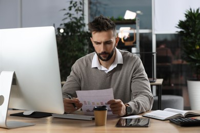 Photo of Man working with document at table in office