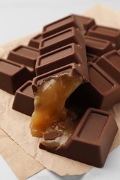 Photo of Tasty chocolate bars with caramel on white table, closeup