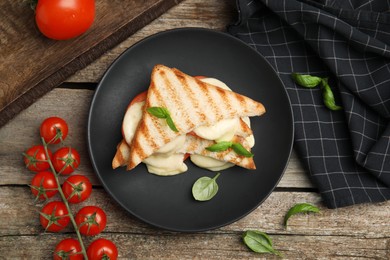 Photo of Delicious grilled sandwiches with mozzarella, tomatoes and basil on wooden table, flat lay