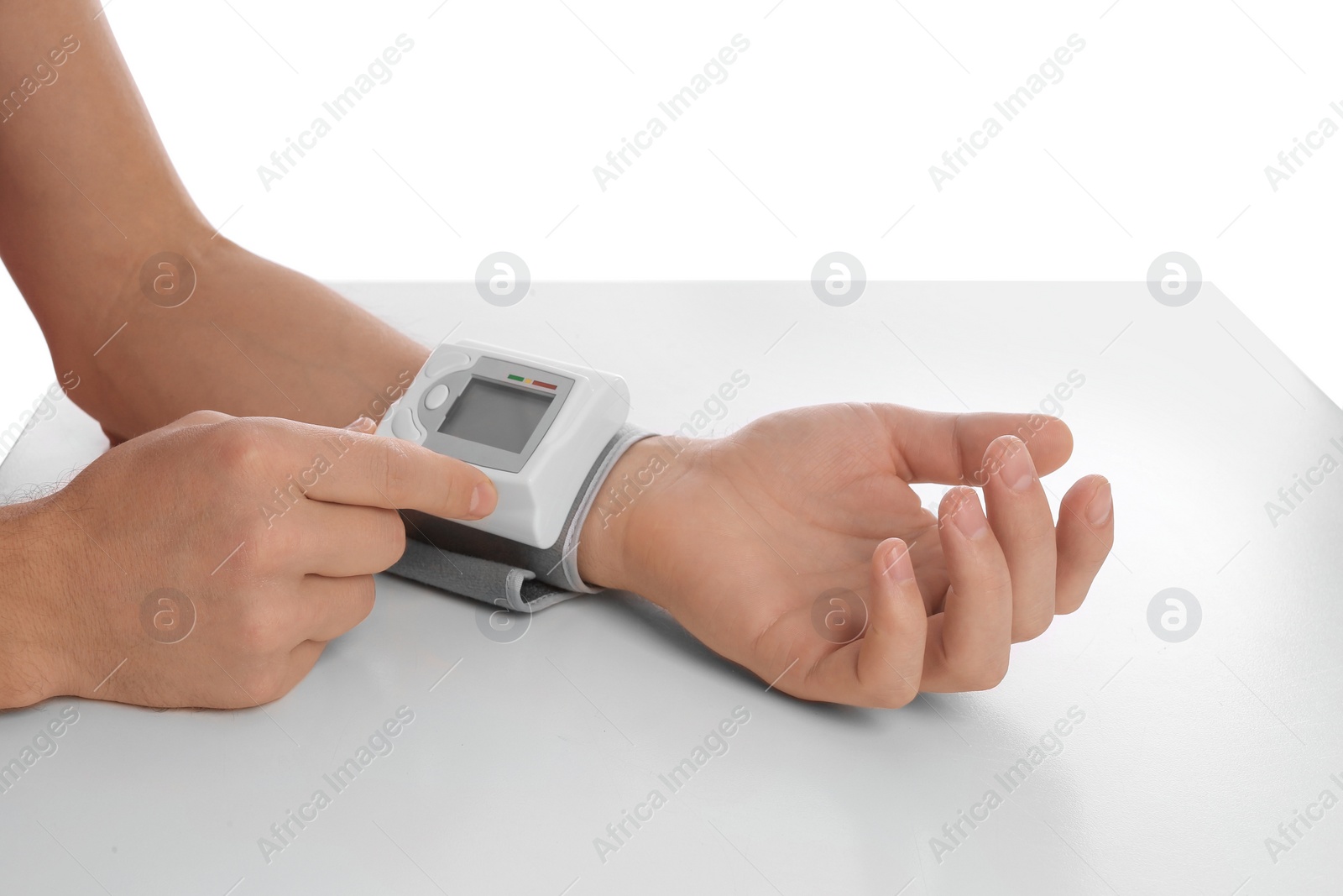 Photo of Man checking blood pressure with sphygmomanometer at table against white background, closeup. Cardiology concept