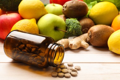 Photo of Dietary supplements. Overturned bottle with pills near food products on light wooden table