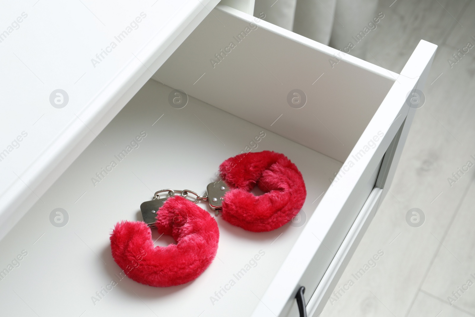 Photo of Fluffy handcuffs in open white drawer. Sex toys