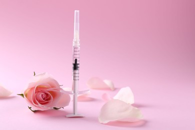 Cosmetology. Medical syringe, rose flower and petals on pink background, space for text