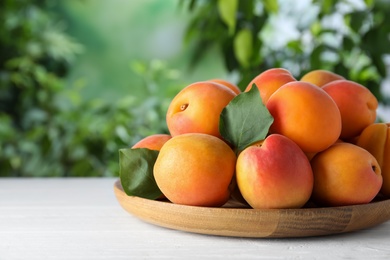 Many fresh ripe apricots on white table against blurred background