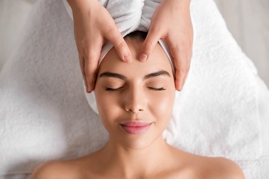 Beautiful woman receiving facial massage in beauty salon, closeup. Top view