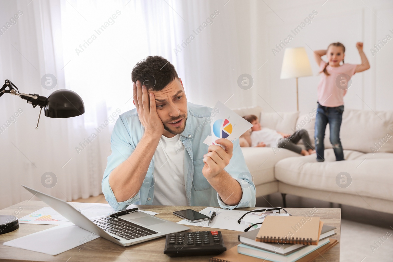 Photo of Overwhelmed man combining parenting and work at home