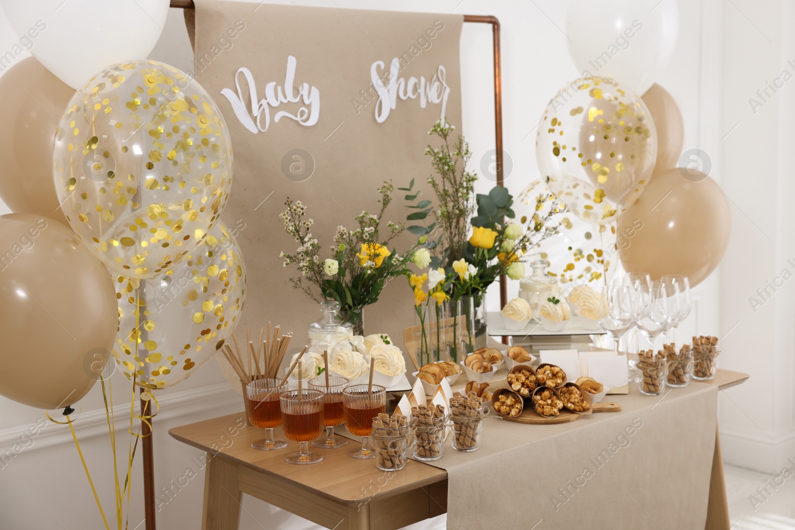 Photo of Tasty treats and glasses of drink on table in room. Baby shower party