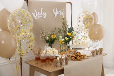 Photo of Tasty treats and glasses of drink on table in room. Baby shower party