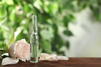 Photo of Pharmaceutical ampoule with medication and flower on wooden table, space for text