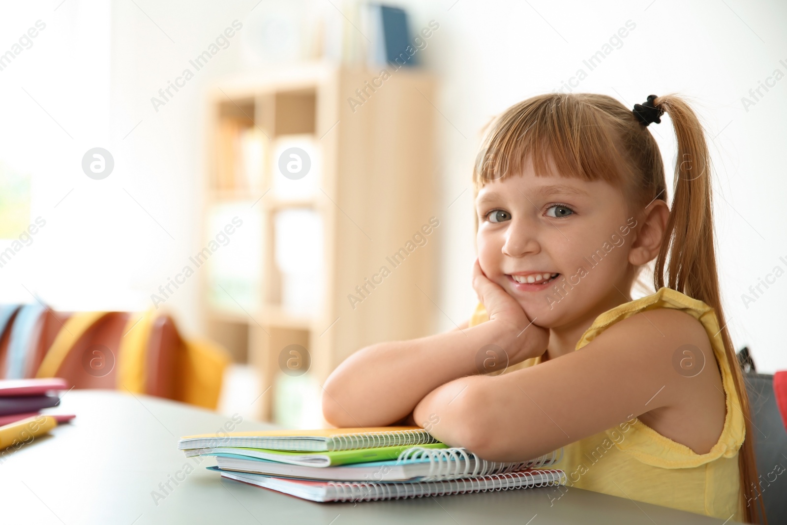 Photo of Cute little child sitting at desk in classroom. Elementary school
