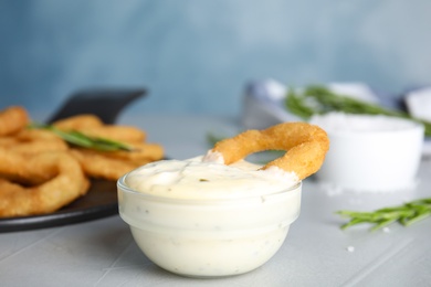 Photo of Fried onion ring with sauce on grey table