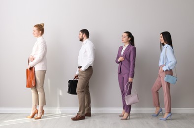 Photo of Businesspeople waiting in queue near light wall indoors