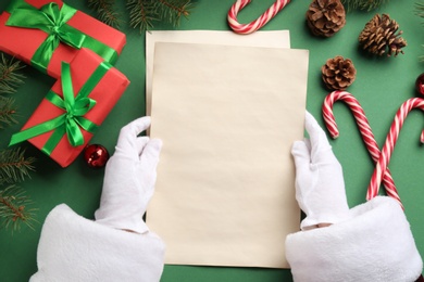 Santa holding letter at green table, top view