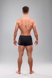 Photo of Muscular man on light grey background, back view. Sexy body