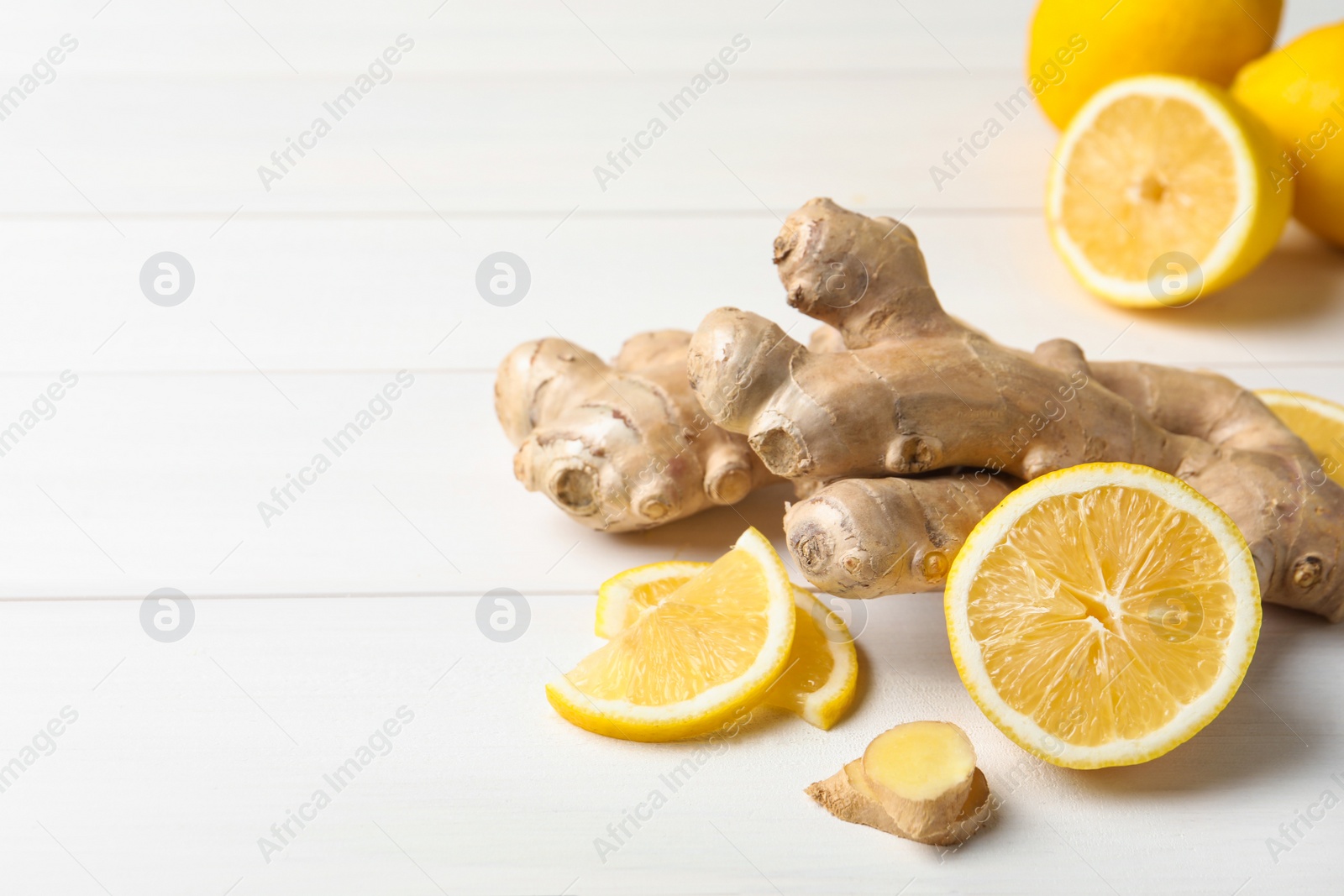 Photo of Fresh lemon and ginger on white wooden table. Space for text