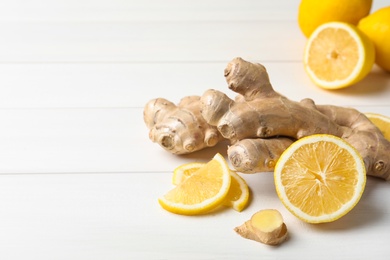 Photo of Fresh lemon and ginger on white wooden table. Space for text