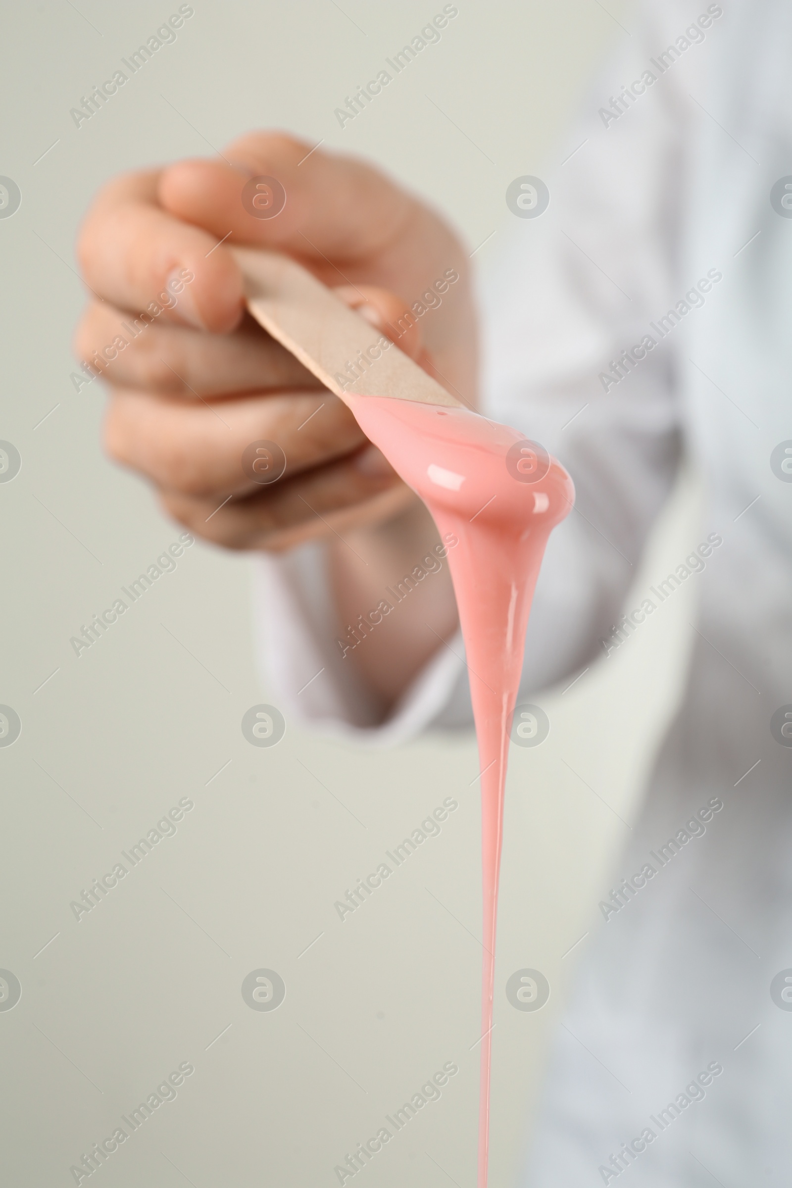 Photo of Woman holding spatula with hot depilatory wax, closeup