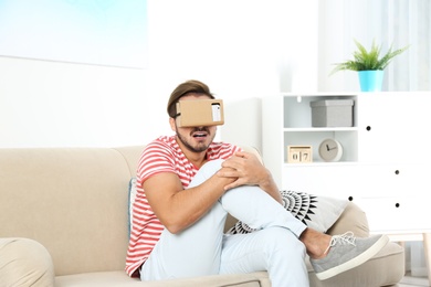 Young man using cardboard virtual reality headset at home