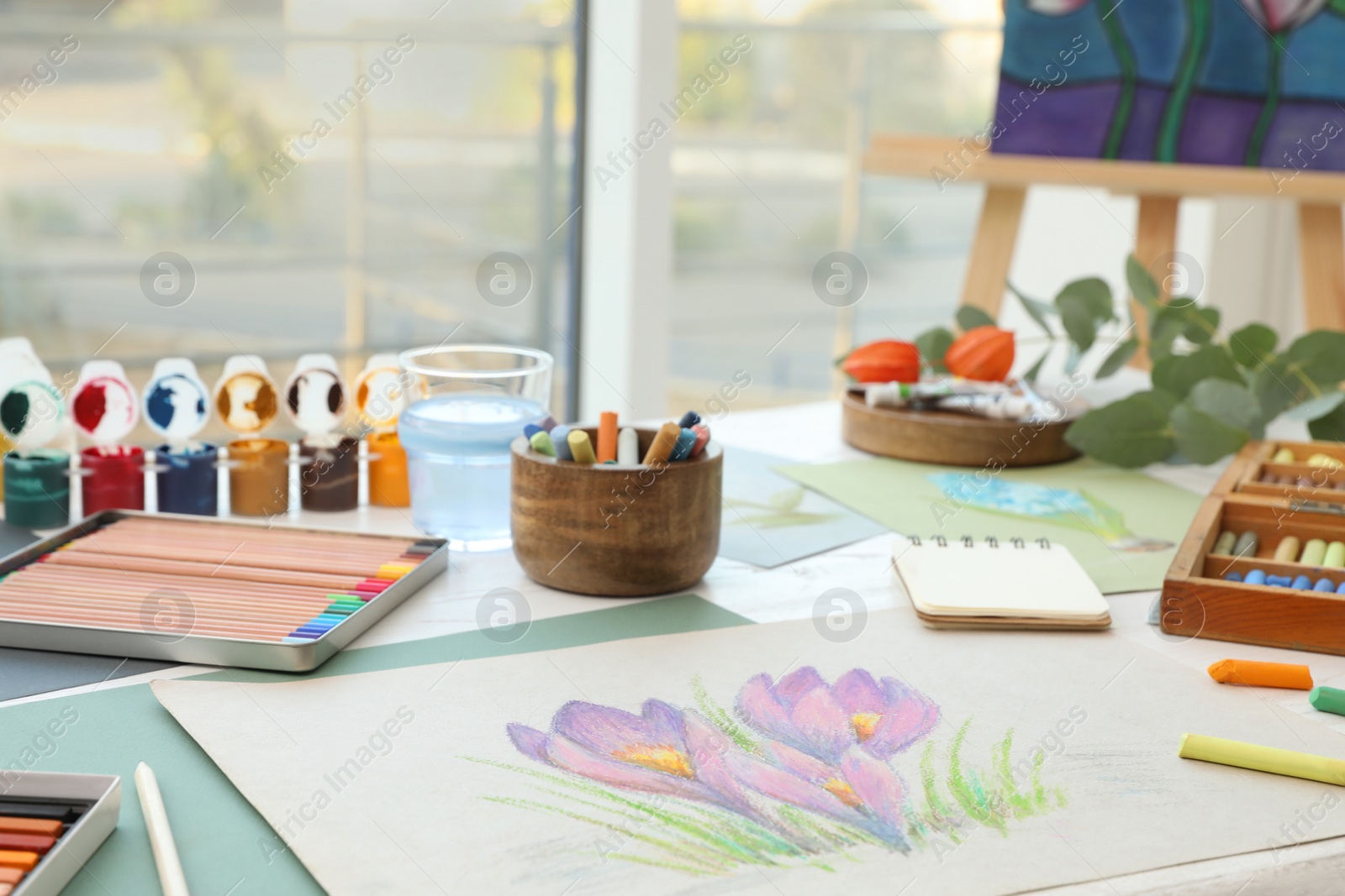 Photo of Artist's workplace with drawing, soft pastels and color pencils on table indoors