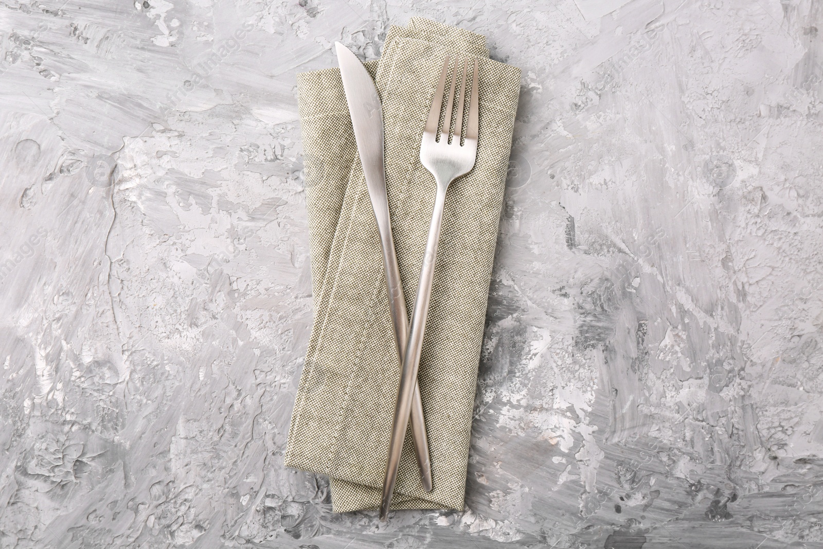 Photo of Elegant silver cutlery and kitchen towel on grey textured table, top view