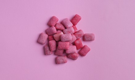 Photo of Heap of tasty sweet chewing gums on pink background, flat lay