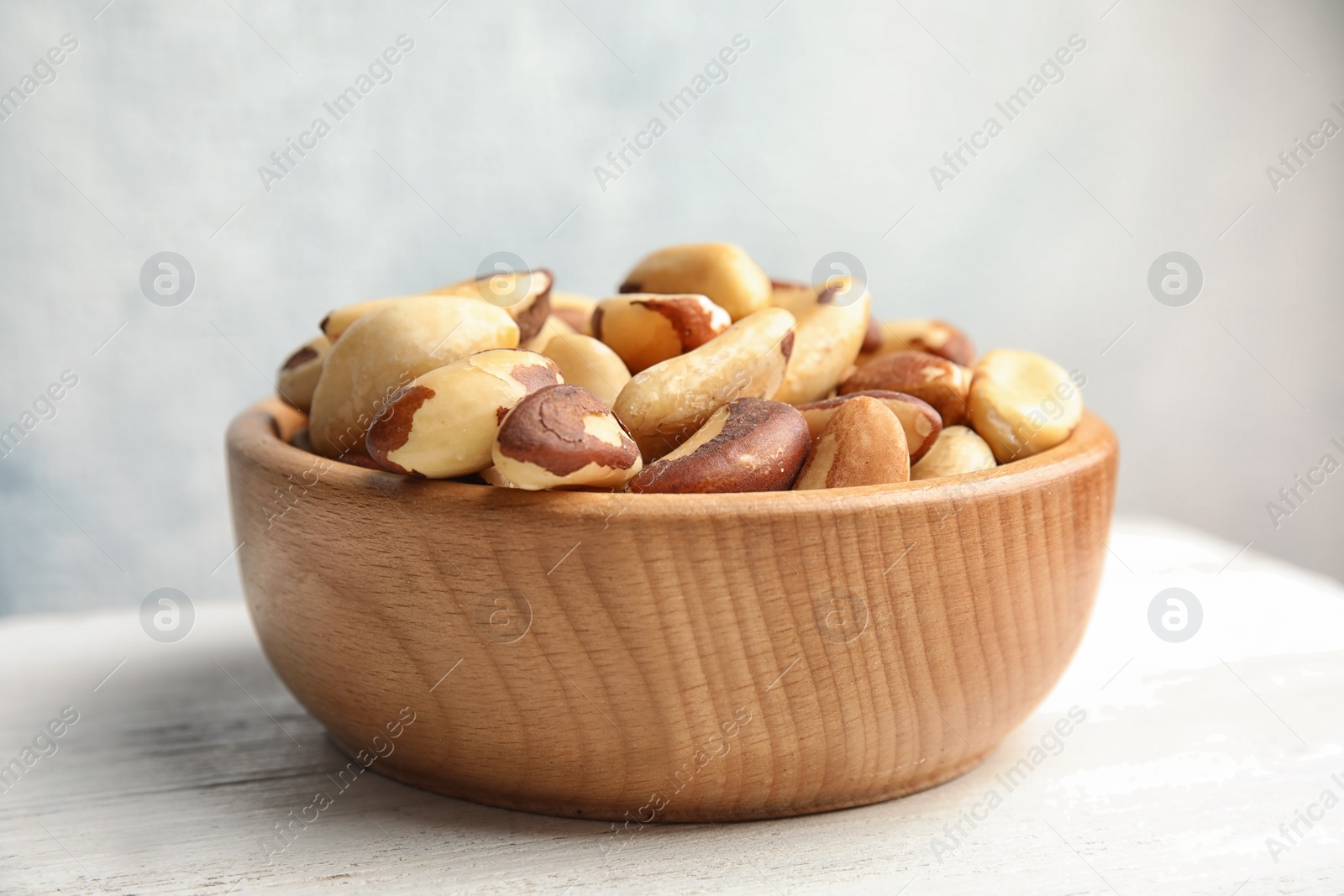 Photo of Bowl with tasty Brazil nuts on white table