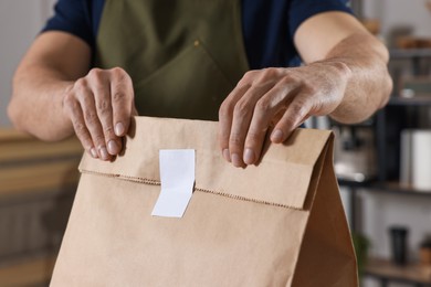 Photo of Worker with paper bag in cafe, closeup