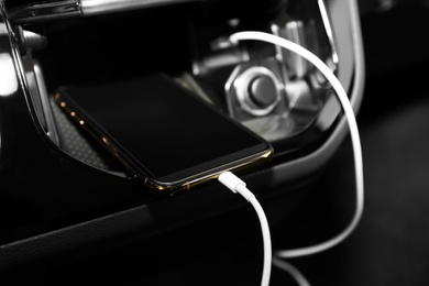 Smartphone with USB charging cable in modern car
