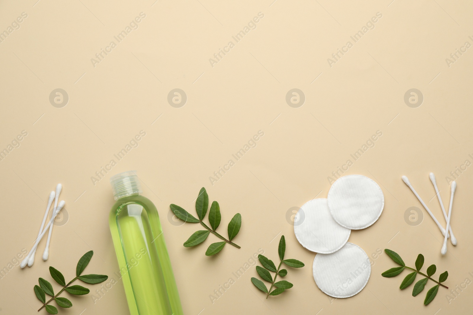 Photo of Cotton pads, swabs, leaves and makeup removal product on beige background, flat lay. Space for text