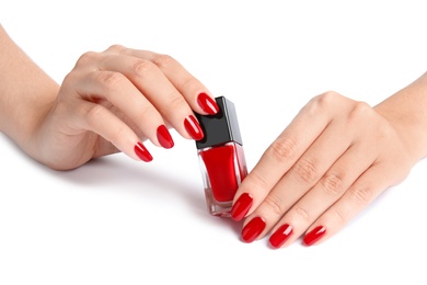 Photo of Woman with bright manicure holding bottle of nail polish on white background, closeup