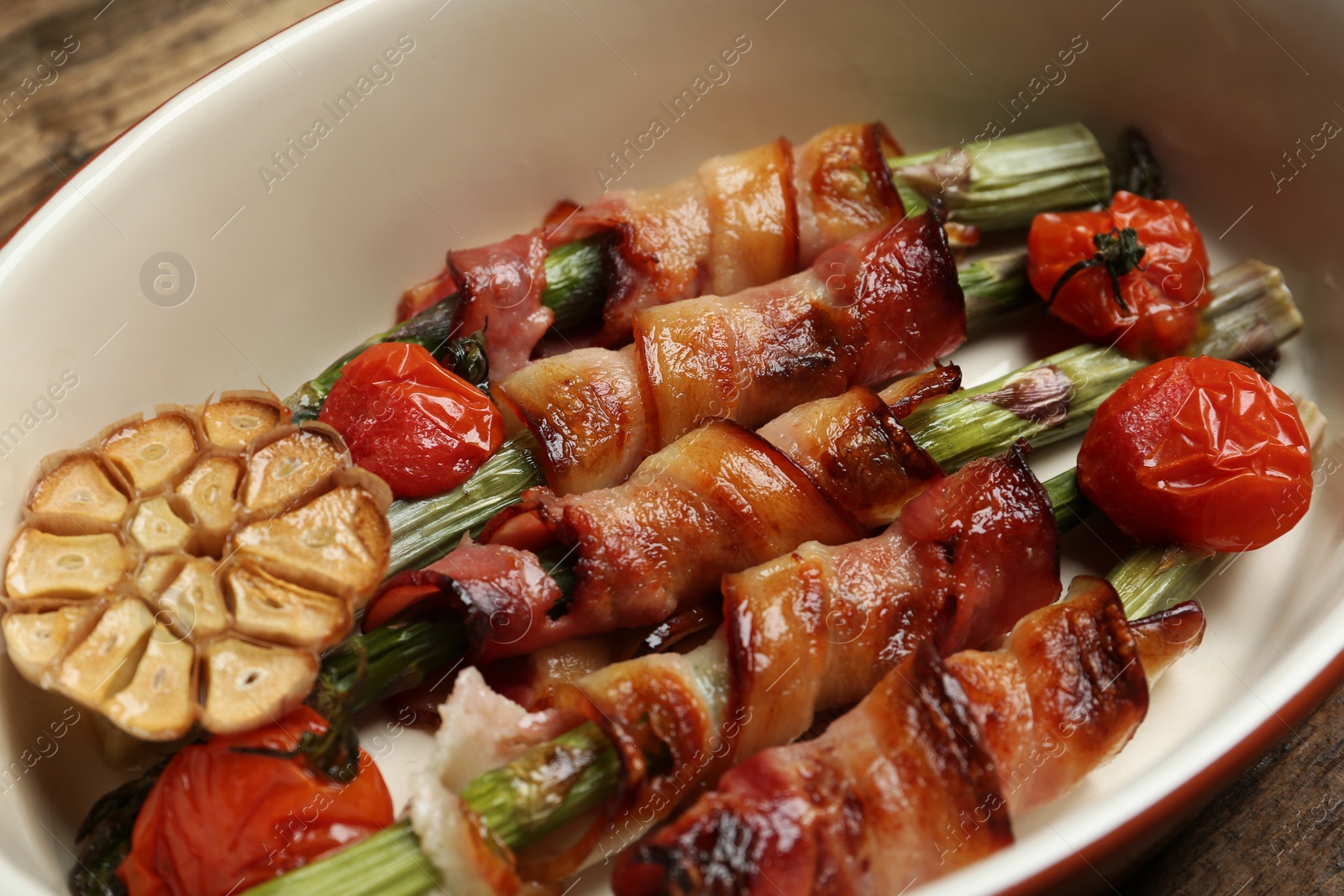 Photo of Oven baked asparagus wrapped with bacon in ceramic dish, closeup