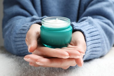 Photo of Woman with jar of hand cream over snow, closeup