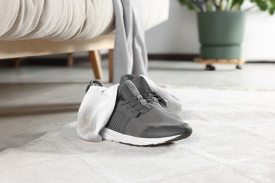 Photo of Sneakers with dirty socks on light carpet indoors