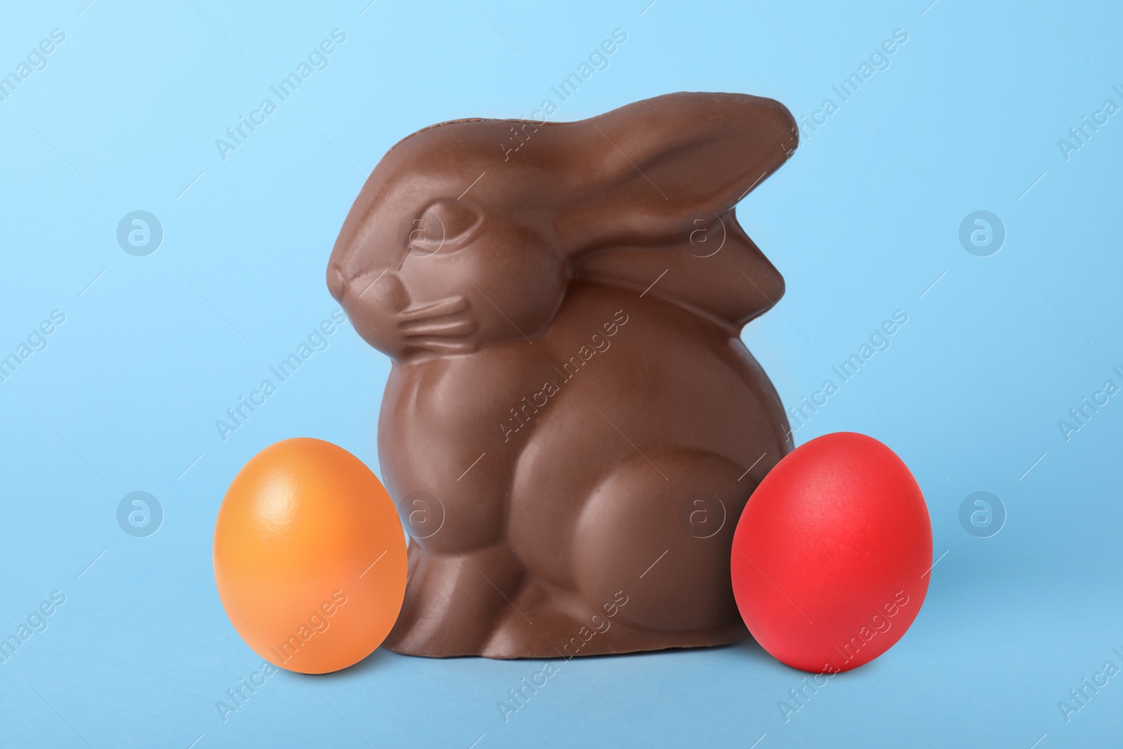 Image of Chocolate bunny and dyed Easter eggs on light blue background