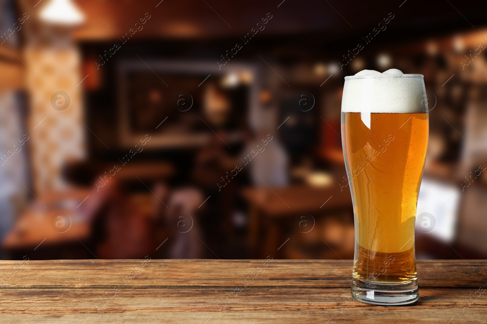 Image of Glass with fresh beer on wooden table in pub, space for text