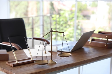 Photo of Scales of justice and laptop on desk in notary's office