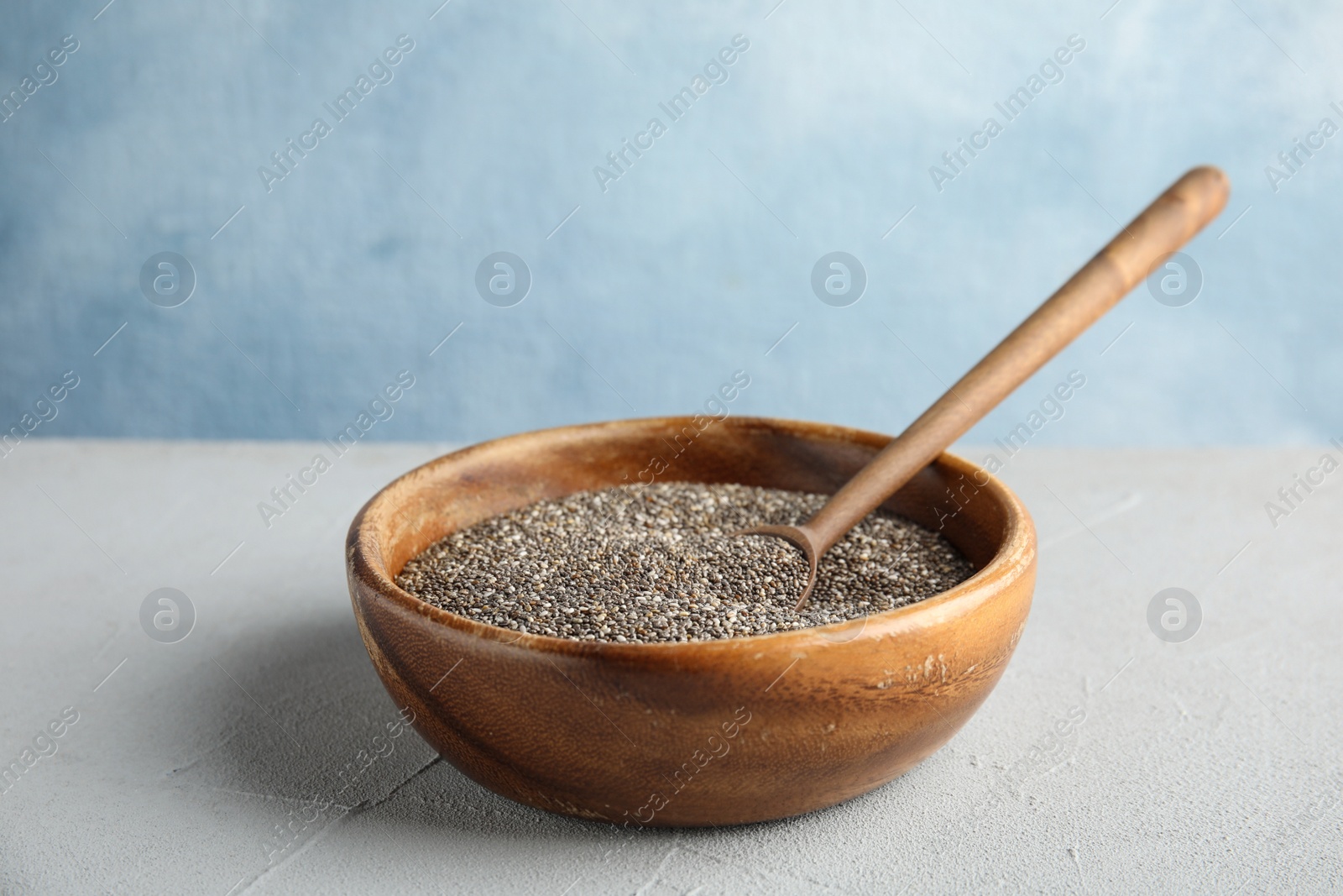 Photo of Bowl and spoon with chia seeds on table against color background