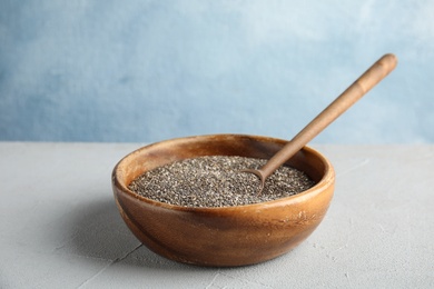 Photo of Bowl and spoon with chia seeds on table against color background