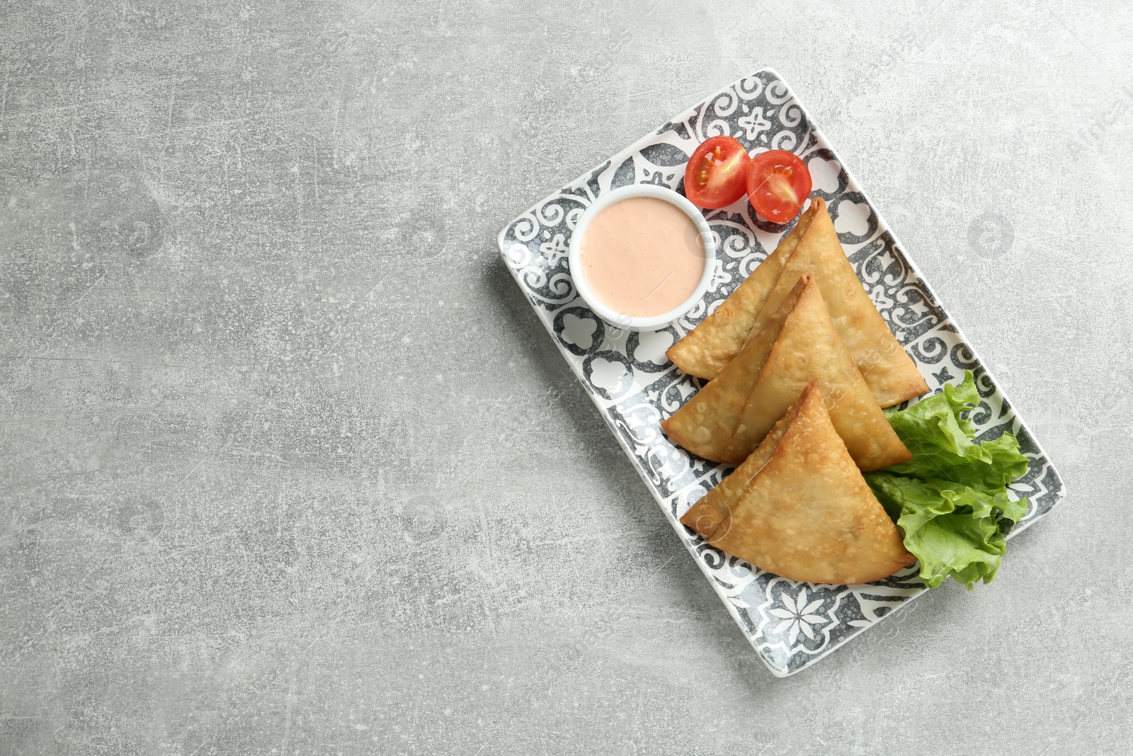 Photo of Fresh delicious crispy samosas served on grey table, top view. Space for text