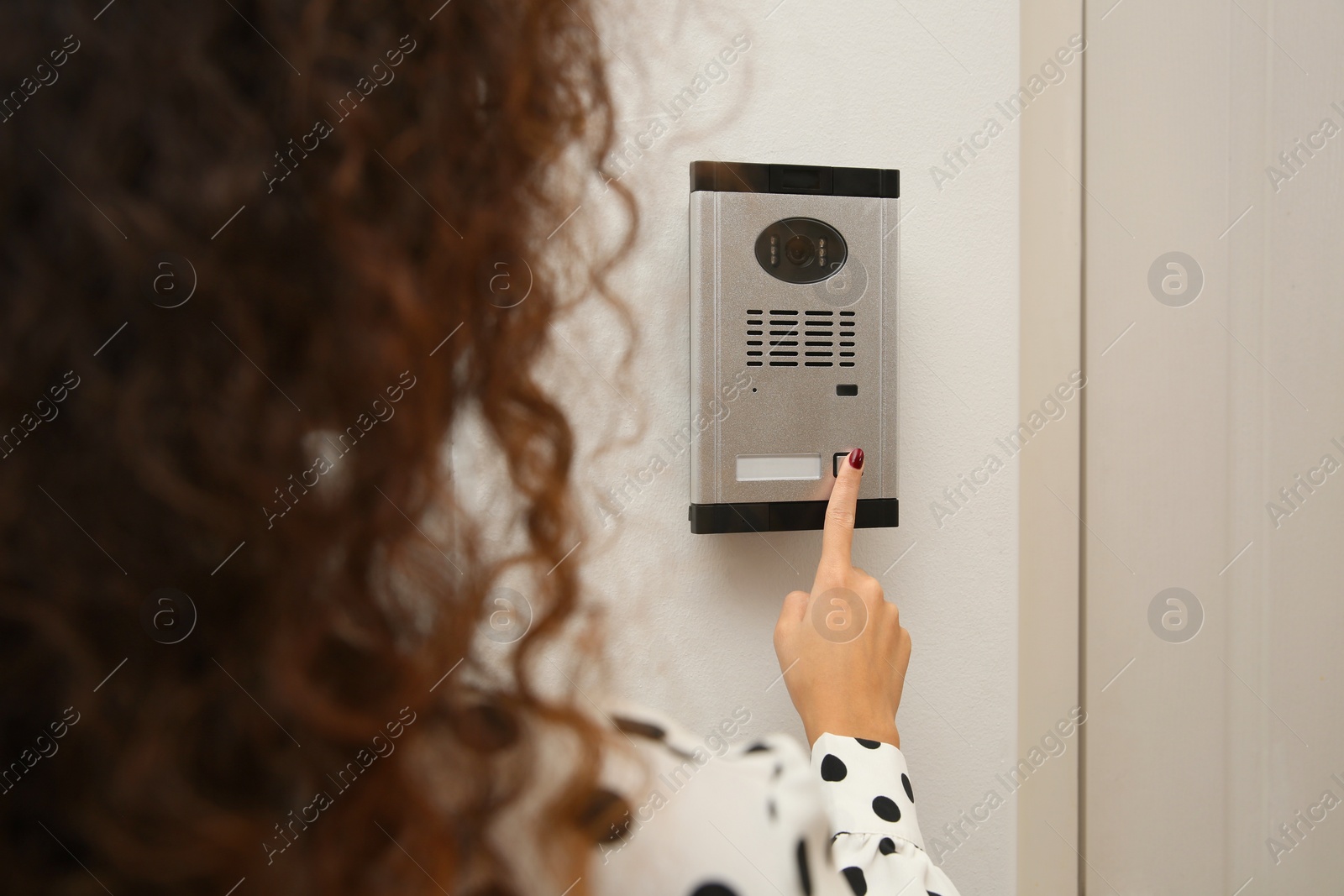 Photo of African-American woman ringing intercom with camera in entryway, closeup