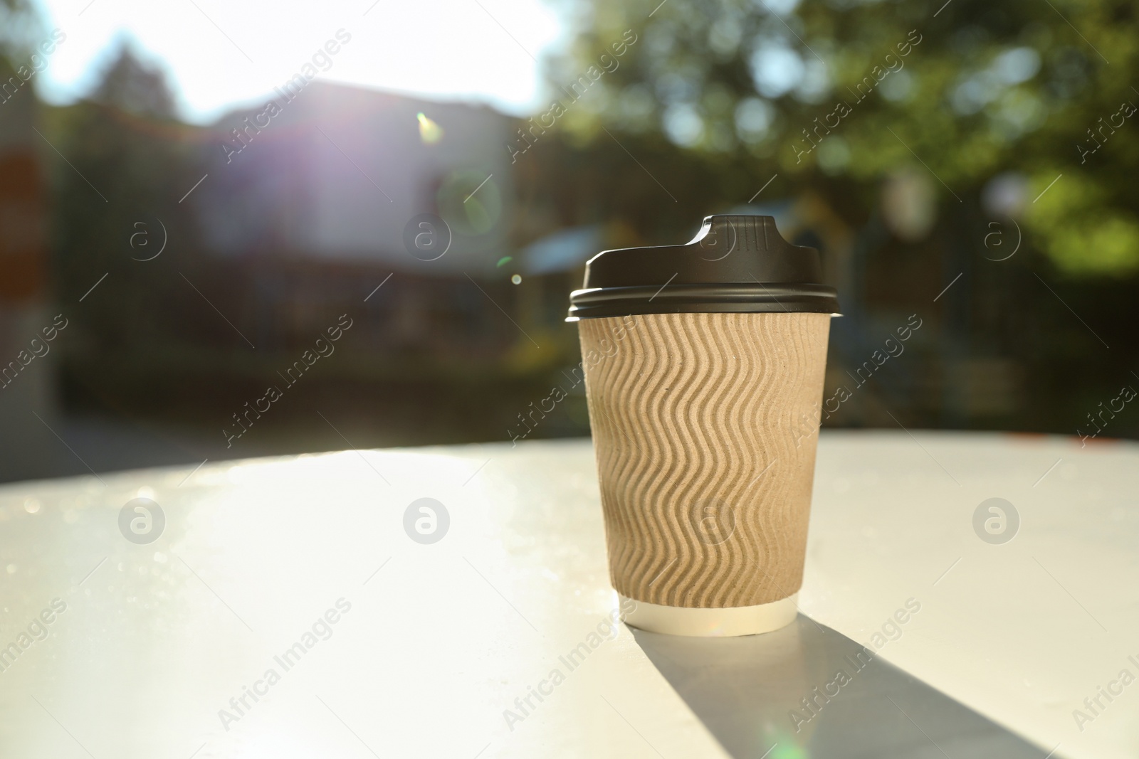 Photo of Cardboard takeaway coffee cup with plastic lid on white table outdoors, space for text