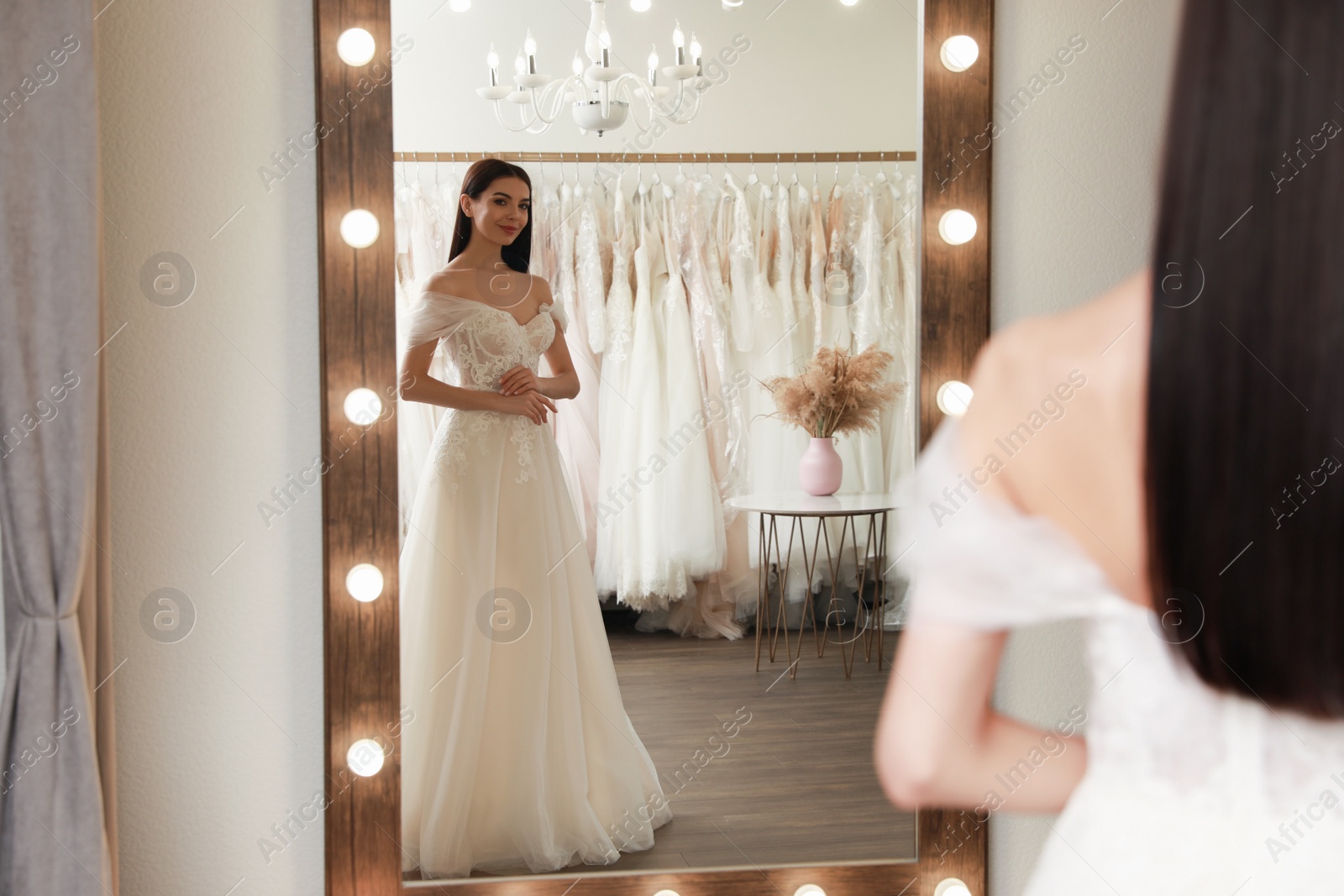 Photo of Woman trying on beautiful wedding dress in boutique