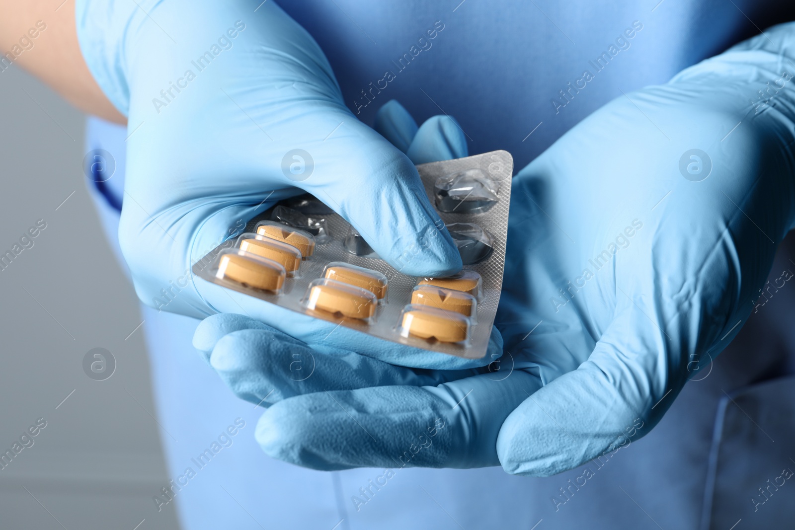 Photo of Doctor taking pill out from blister pack on grey background, closeup